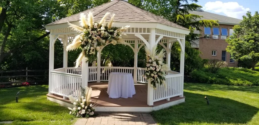 White garden gazebo decorated with florals for outdoor wedding ceremony